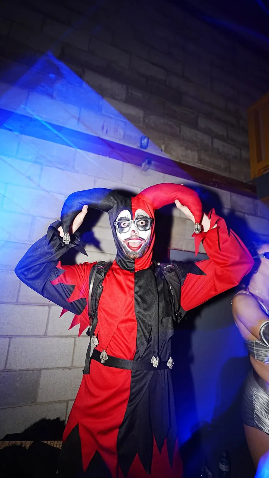 A guest in red-and-black jester costume and face paint at Halloween 2025